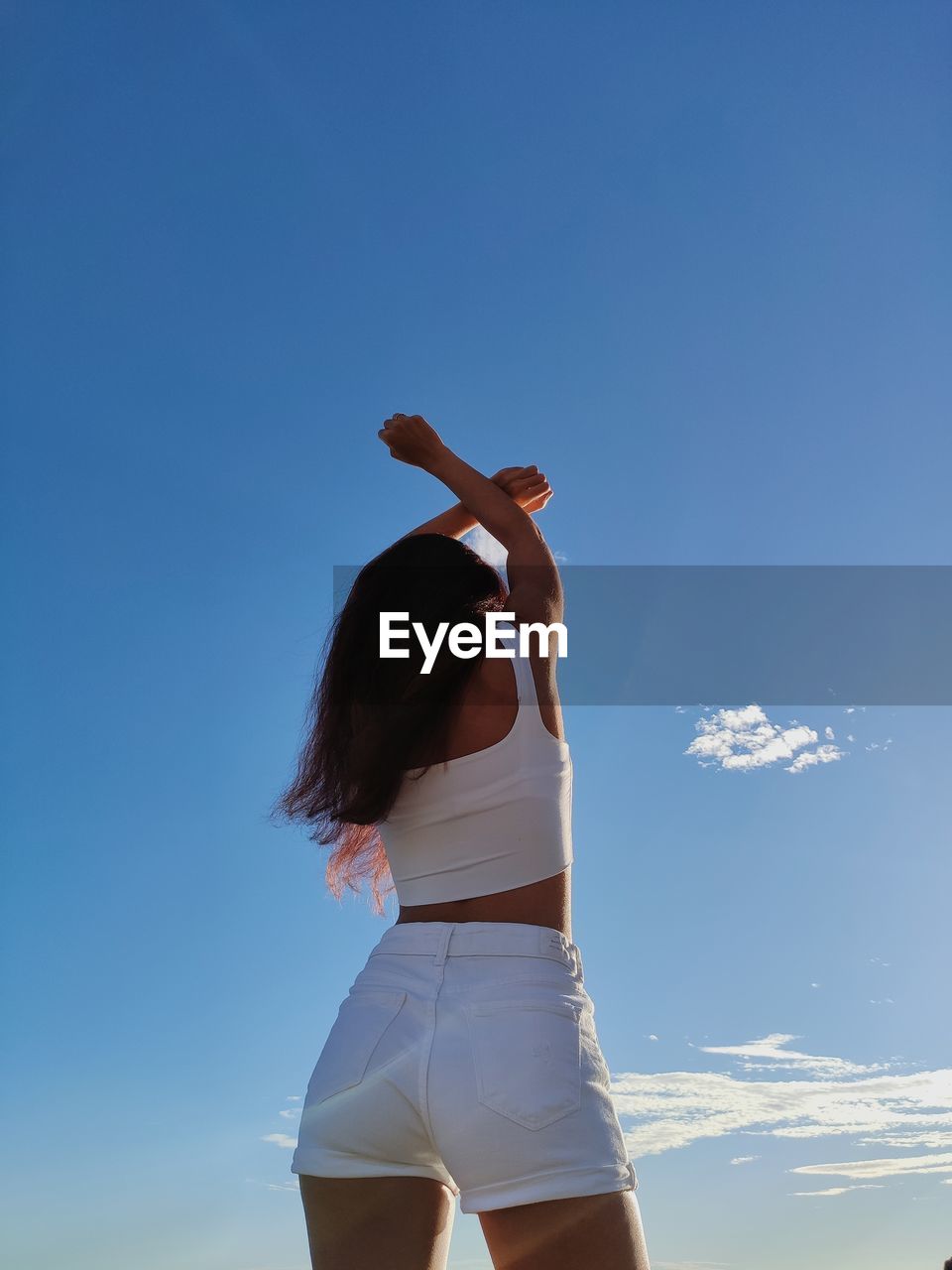 Rear view of woman standing against blue sky