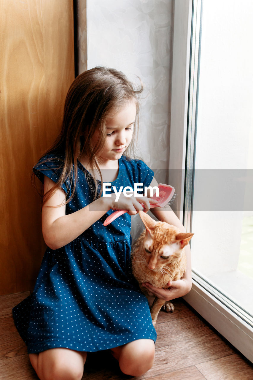 Cute girl sitting by door with cat