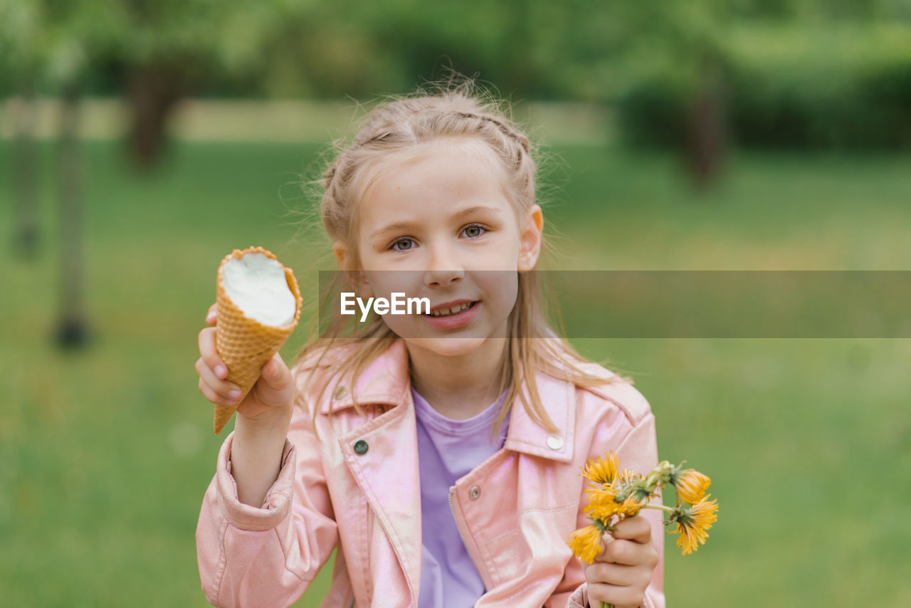 Child girl holds an ice cream cone in her hands in the spring in the park