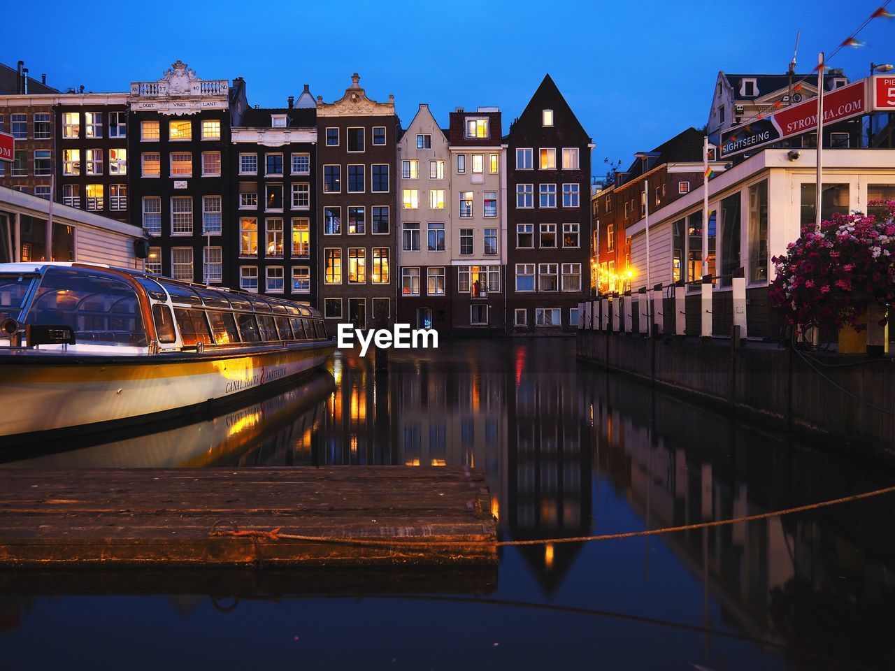 CANAL BY ILLUMINATED BUILDINGS AGAINST SKY AT NIGHT