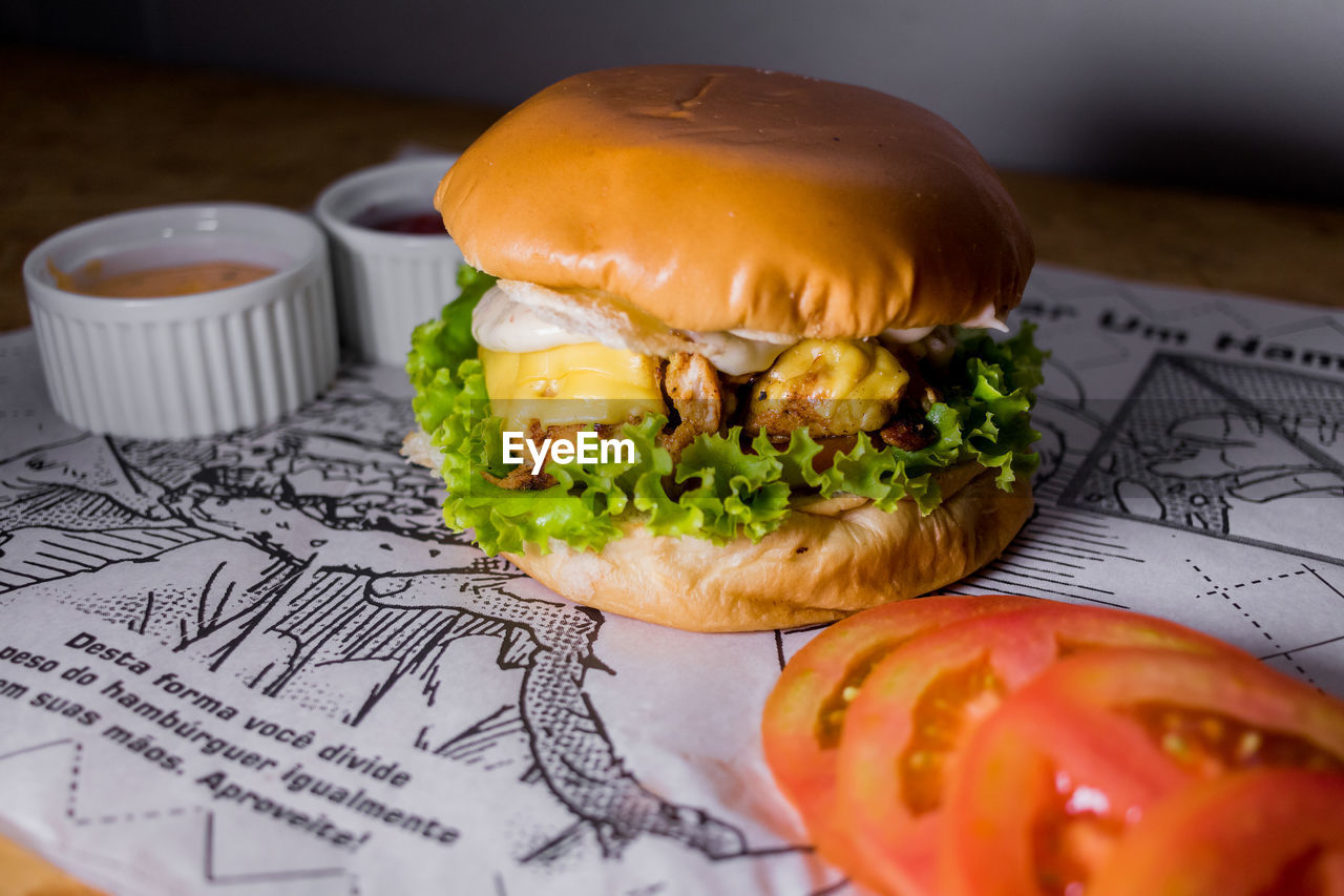 CLOSE-UP OF BURGER ON TABLE AGAINST WALL