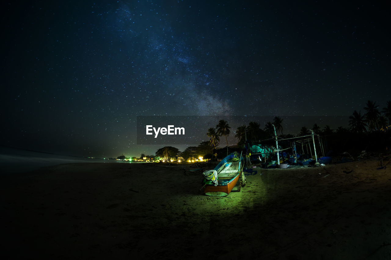 Illuminated beach against sky at night