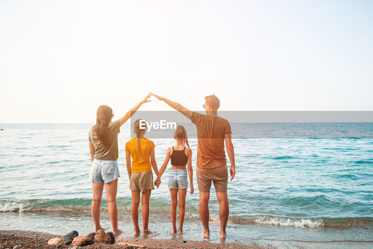 People standing on beach by sea against sky