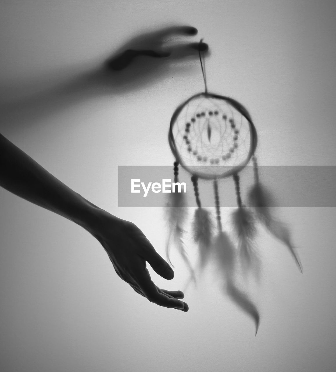 Cropped image of hand holding dreamcatcher indoors