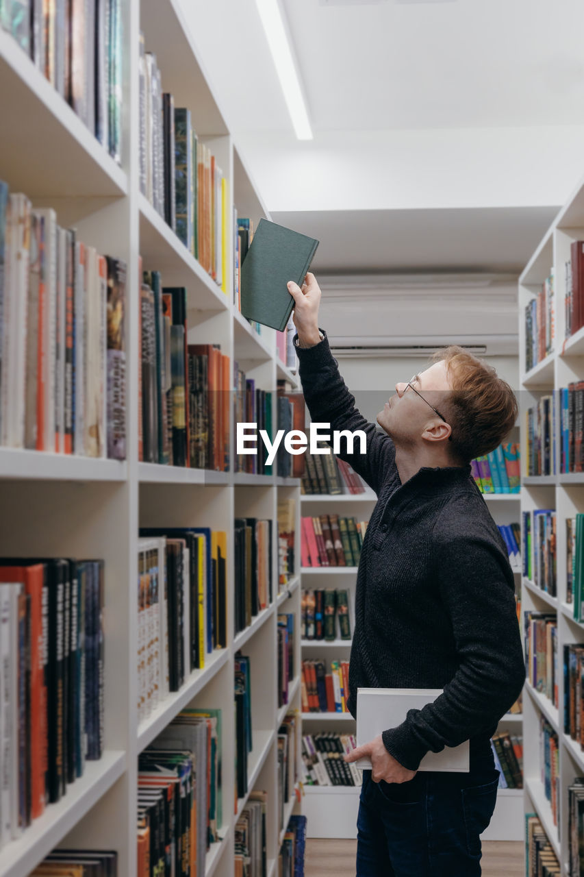 portrait of young woman standing in shelf at library