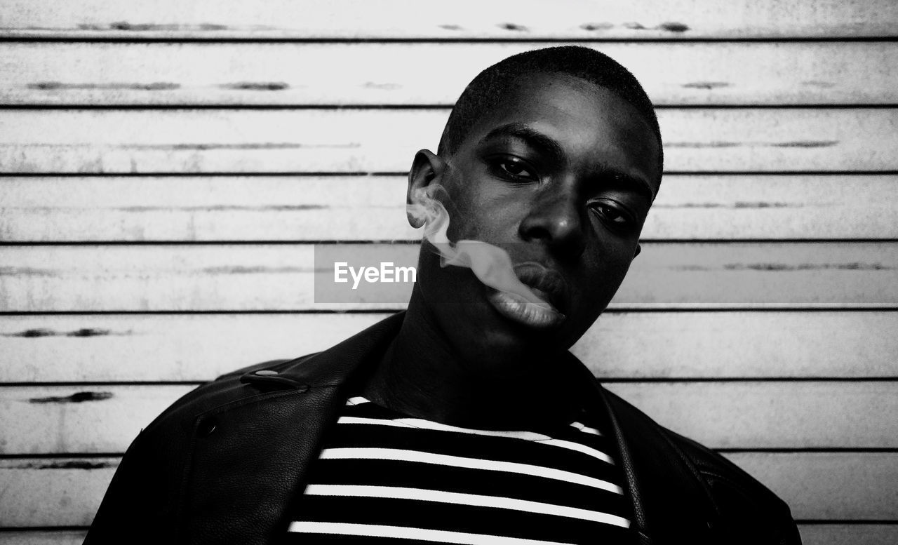 PORTRAIT OF YOUNG MAN AGAINST WALL