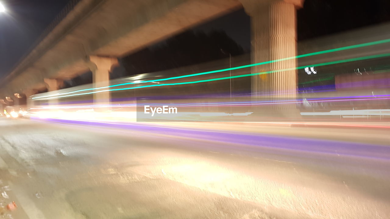 LIGHT TRAILS ON STREET IN CITY AT NIGHT