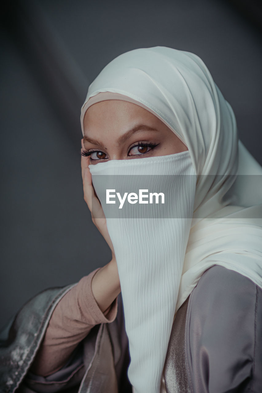Close up portrait of veiled muslim woman wearing white hijab and niqab from high angle.