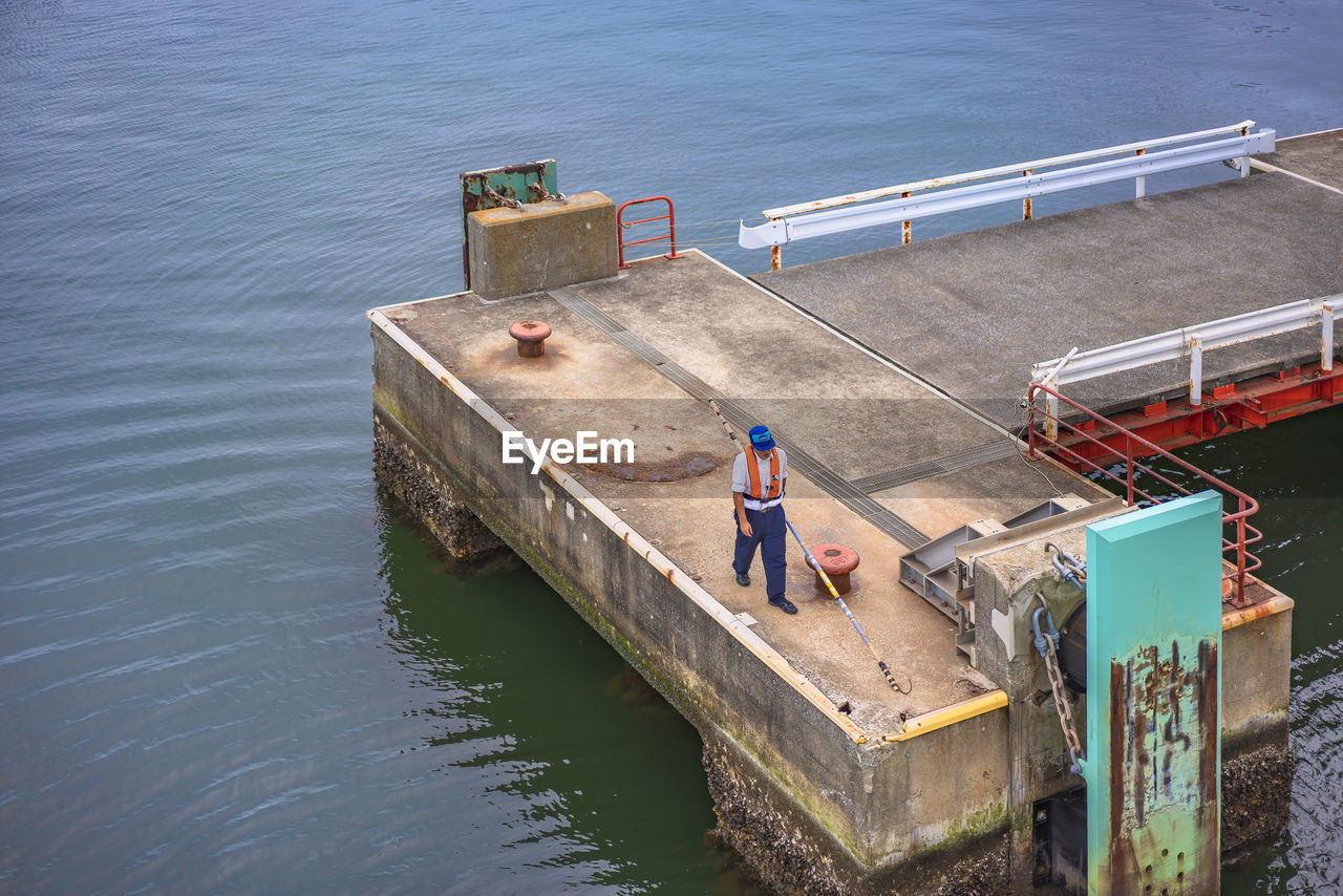 HIGH ANGLE VIEW OF MAN STANDING ON SEA SHORE