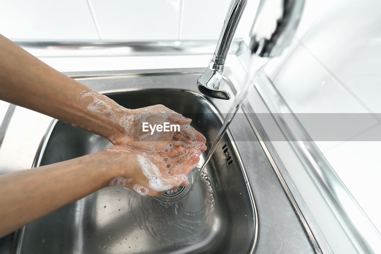 Close-up of person washing hands in sink