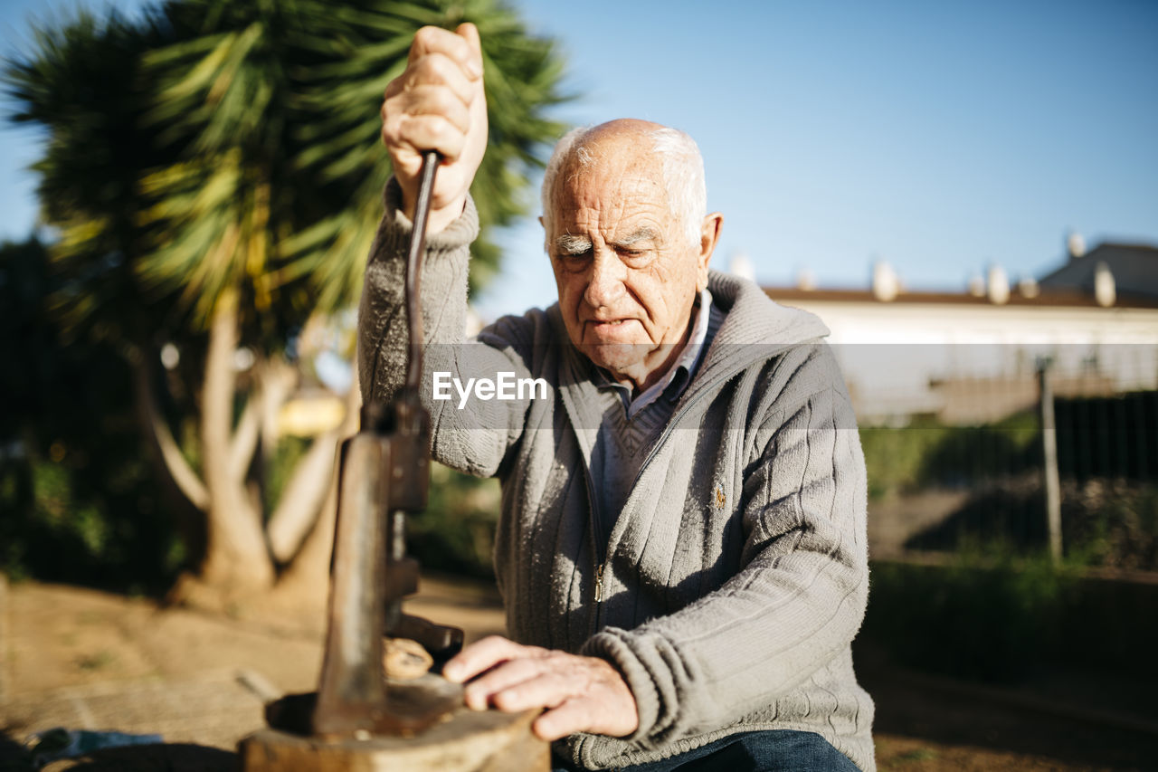 Senior man using an old tool for cracking walnuts