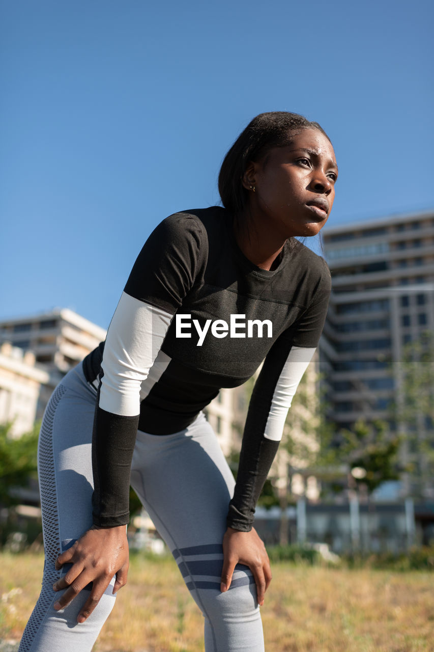 Tired african american runner resting on street