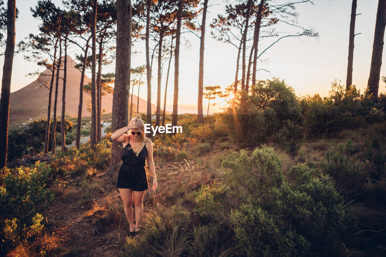 Woman standing against trees during sunset