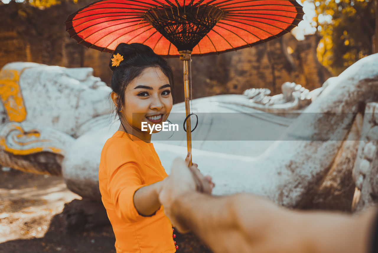 PORTRAIT OF YOUNG WOMAN HOLDING UMBRELLA