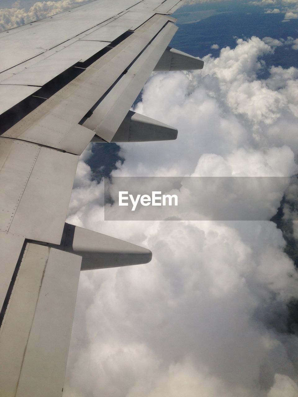 CROPPED IMAGE OF AIRPLANE WING OVER CLOUDS