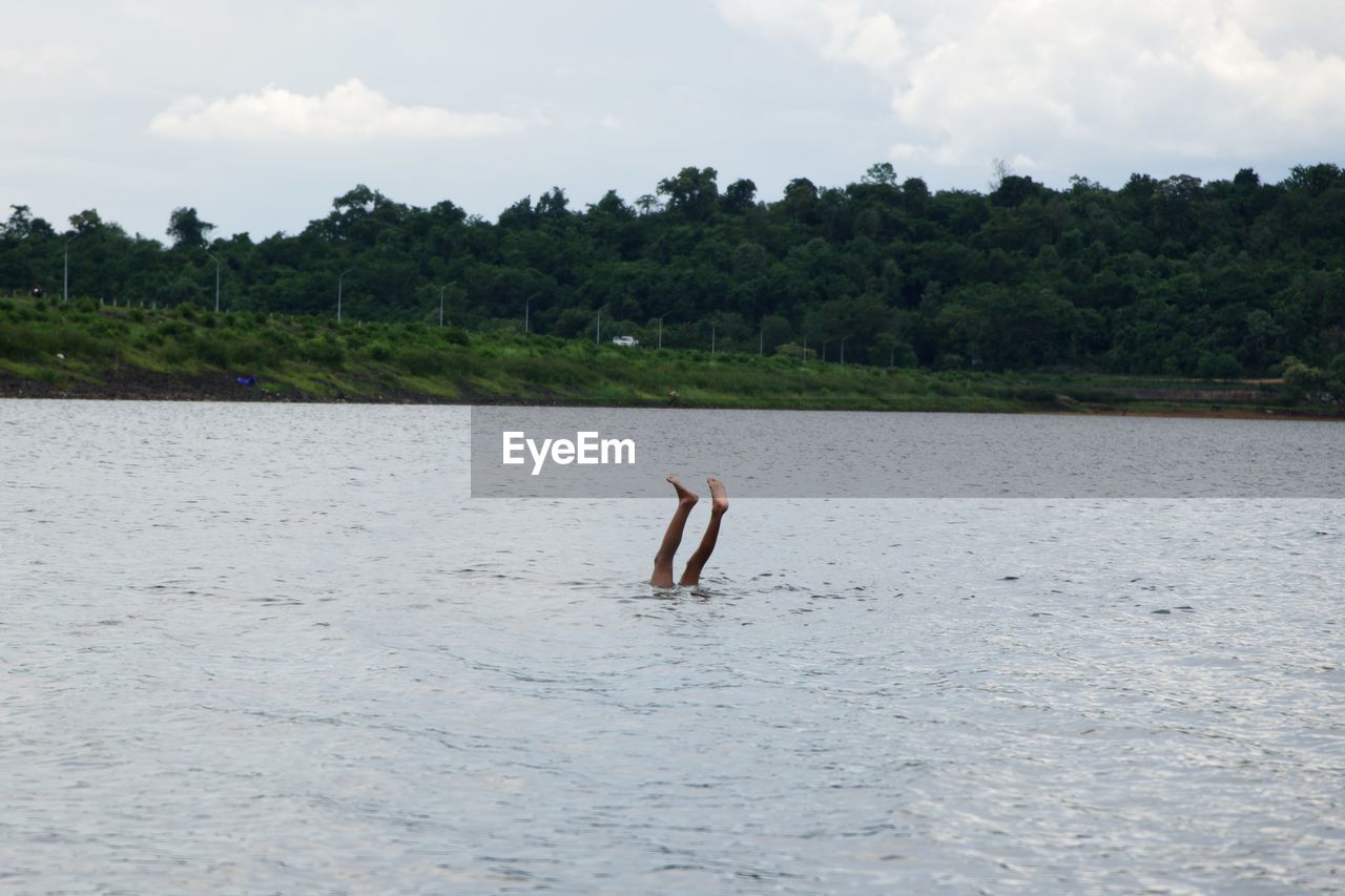Low section of man in river against sky