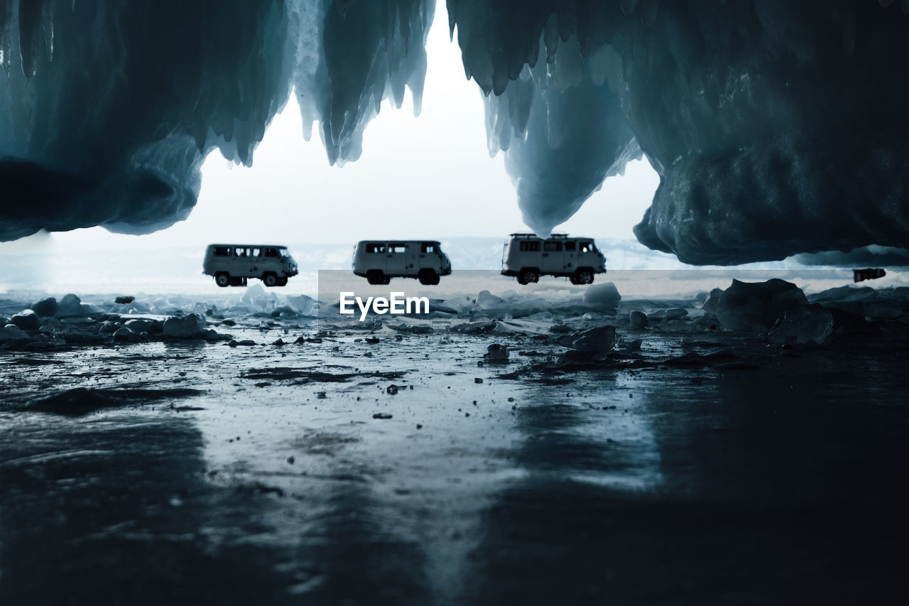 Scenic view of frozen lake with three vans from rock 