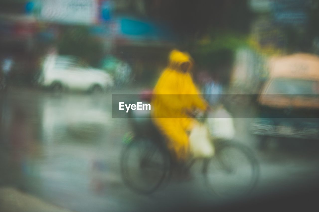 Defocused image of man riding bicycle on street