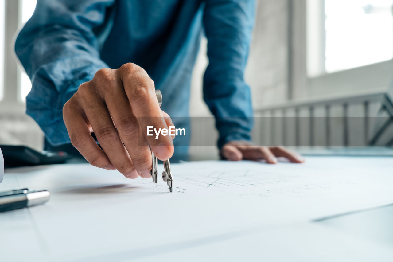 MIDSECTION OF MAN WORKING AT TABLE