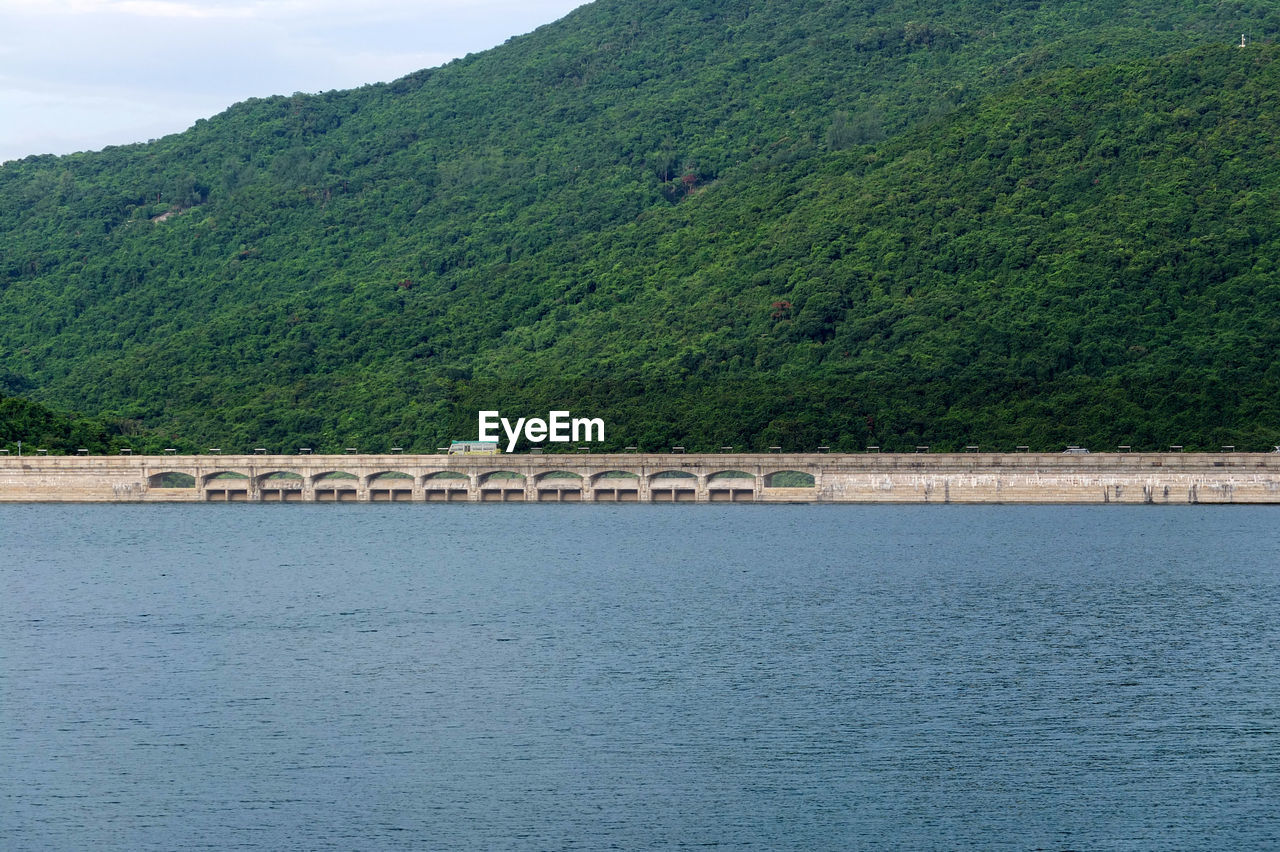 Scenic view of river by mountains against sky