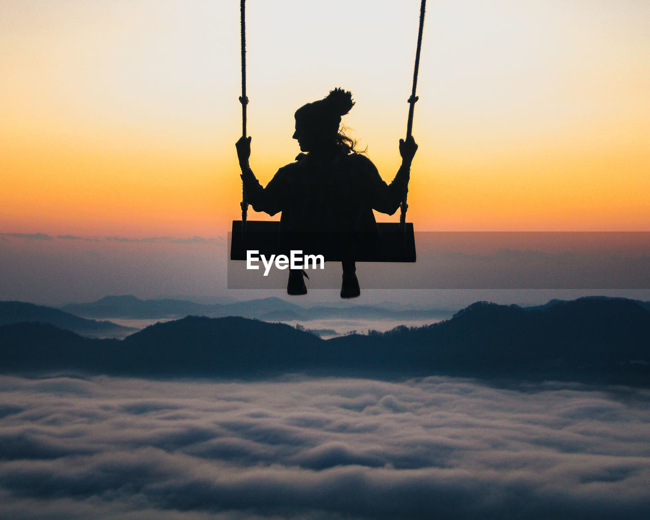 Low angle view of man swinging at sunset