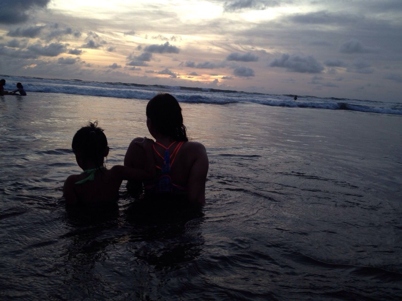 People at beach against cloudy sky