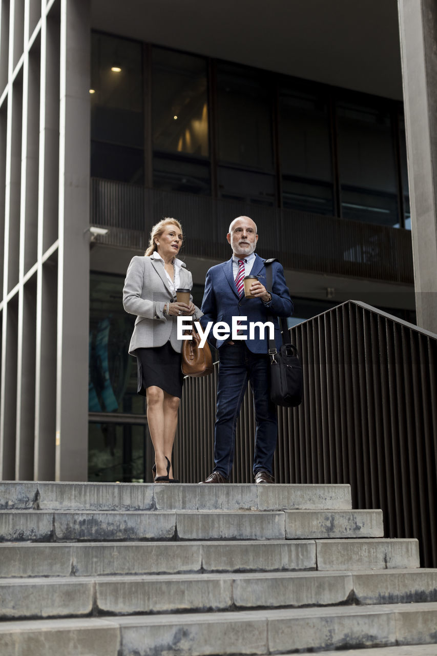 Senior businessman and businesswoman talking outside office building in the city