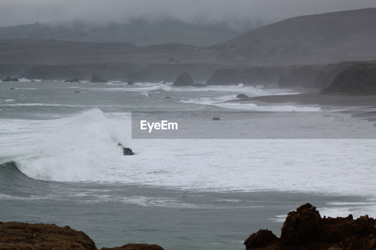 SCENIC VIEW OF SEA AGAINST MOUNTAIN