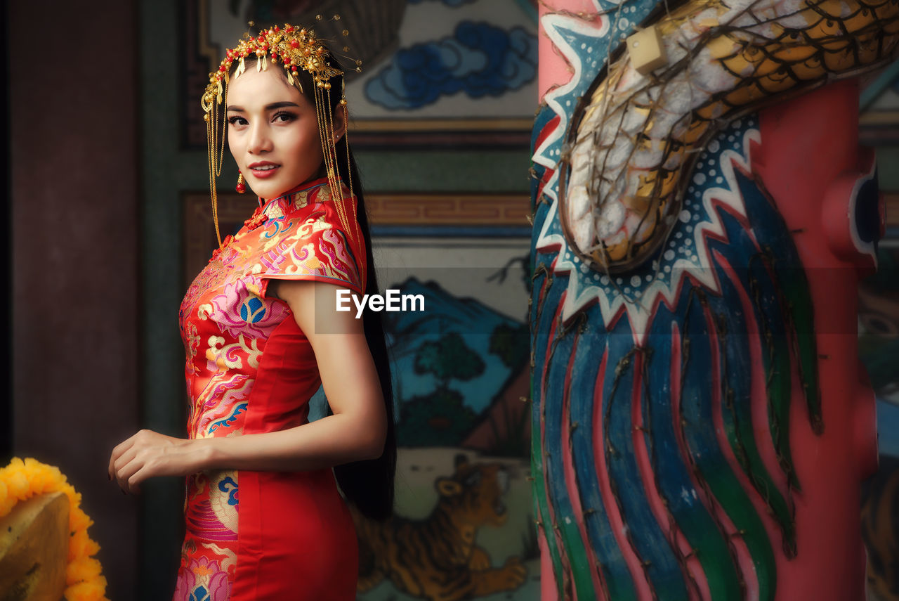 Beautiful asian woman in chinese dress traditional with congratulate gesture in chinese new year