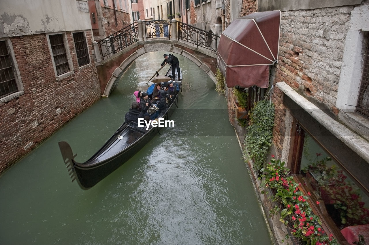 High angle view of people in gondola on canal amidst buildings