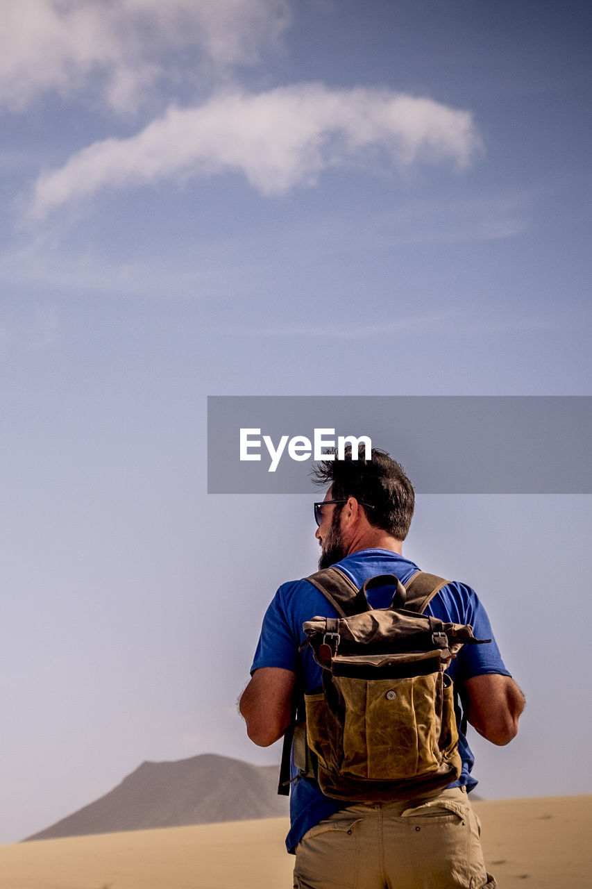 rear view of man standing on beach against sky