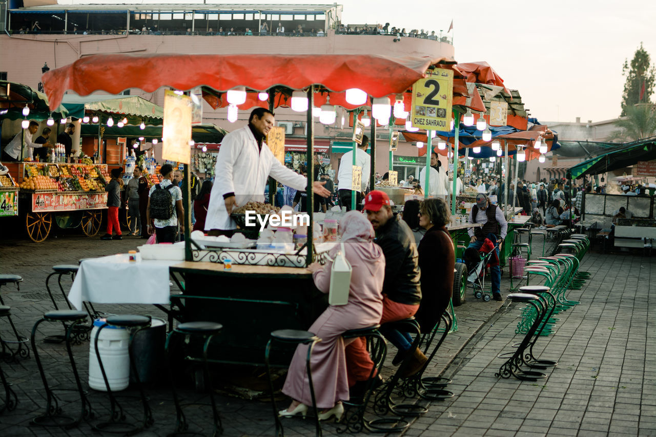 GROUP OF PEOPLE AT MARKET STALL