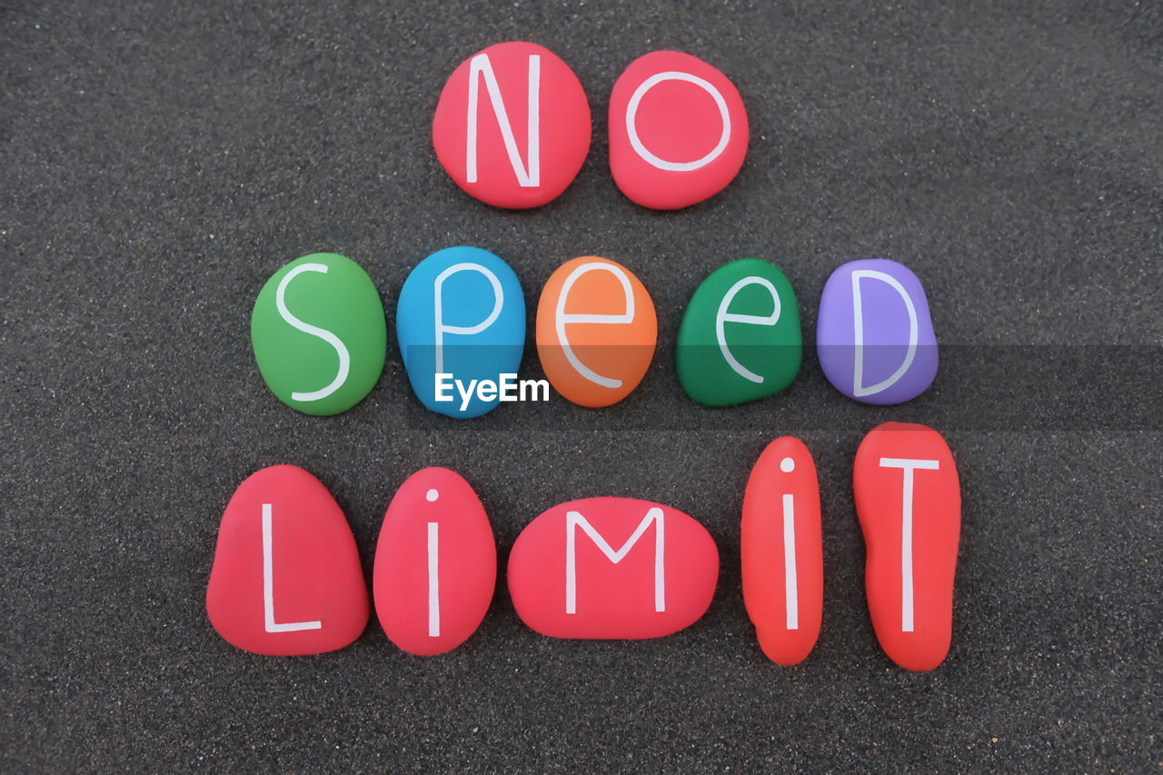 Directly above shot of pebbles with text on sand