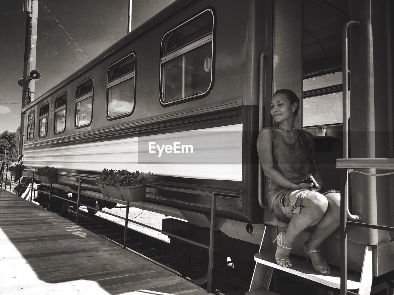 Full length of mid adult woman sitting at doorway in train