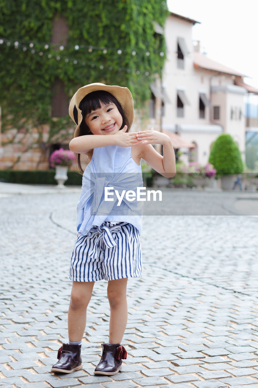 Full length portrait of smiling girl gesturing outdoors