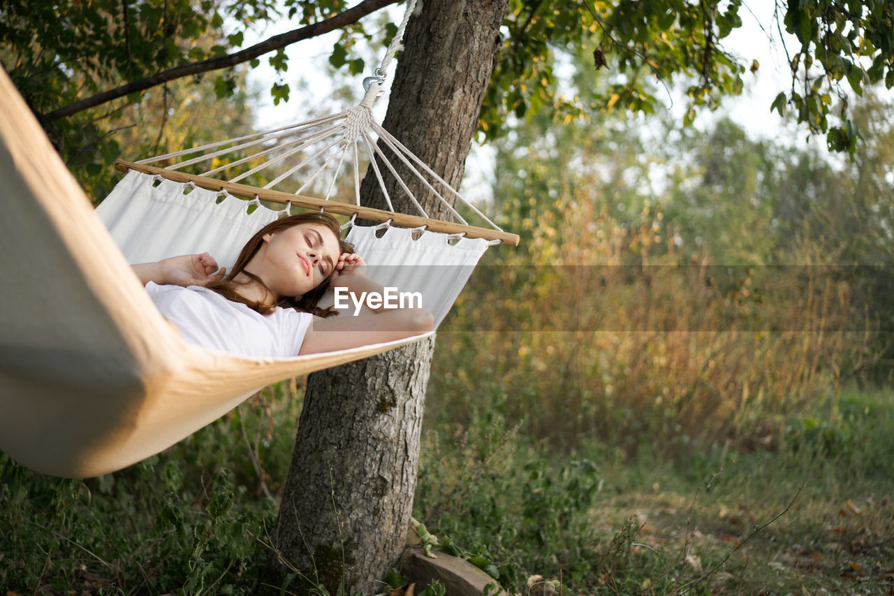 Young woman sitting on hammock in forest