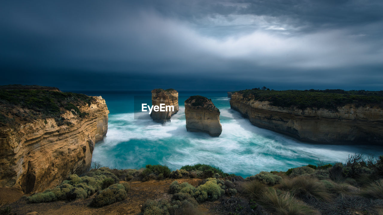Scenic view of sea and rock formations against dramatic sky
