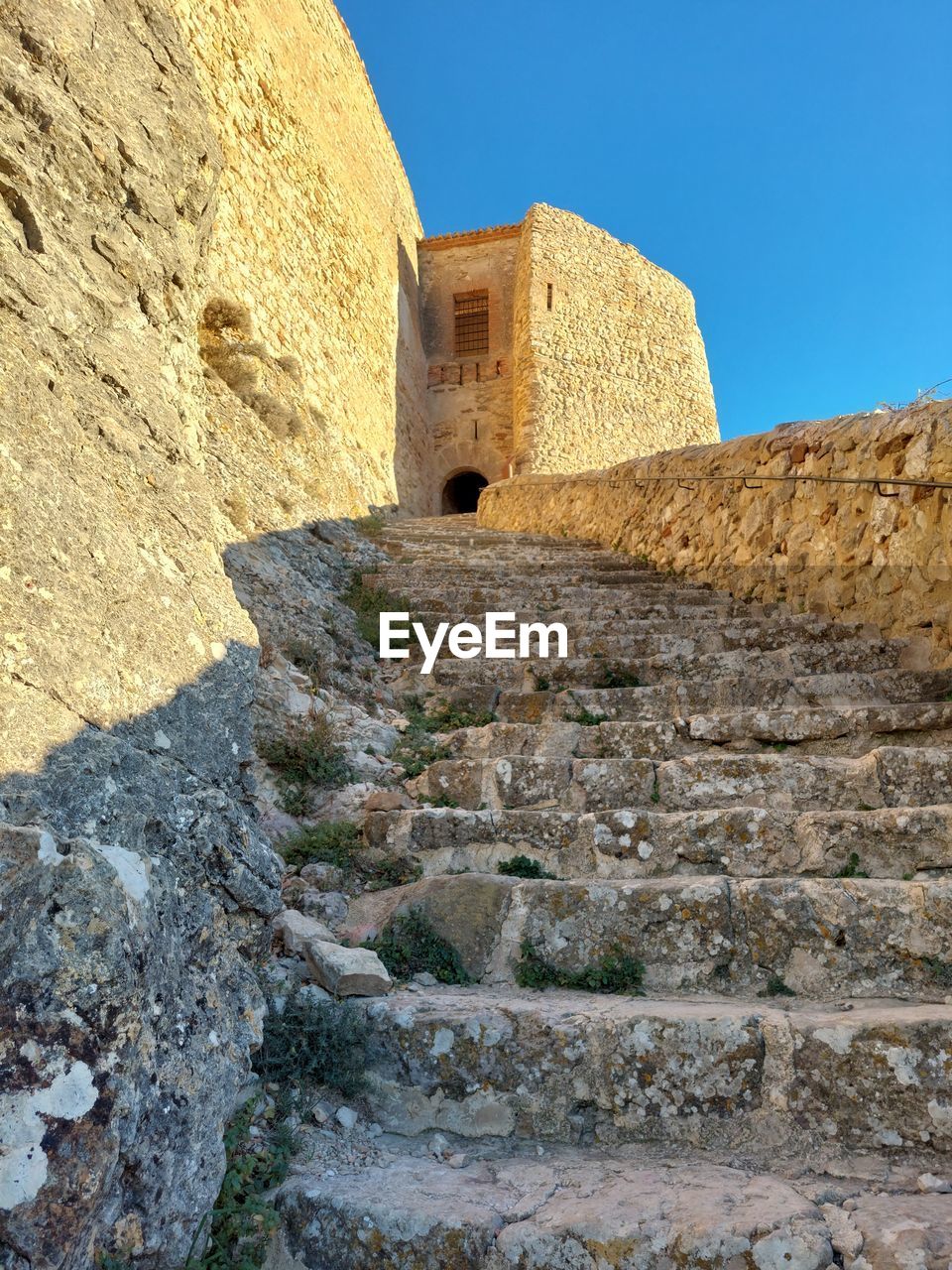 rock, architecture, history, the past, built structure, nature, ancient history, ancient, no people, land, travel destinations, old ruin, wall, ruins, day, travel, building exterior, sky, geology, outdoors, temple, ancient civilization, sunlight, building, terrain, clear sky, wadi, tourism, scenics - nature, formation, old, stone material, blue, sunny, landscape, mountain, rock formation