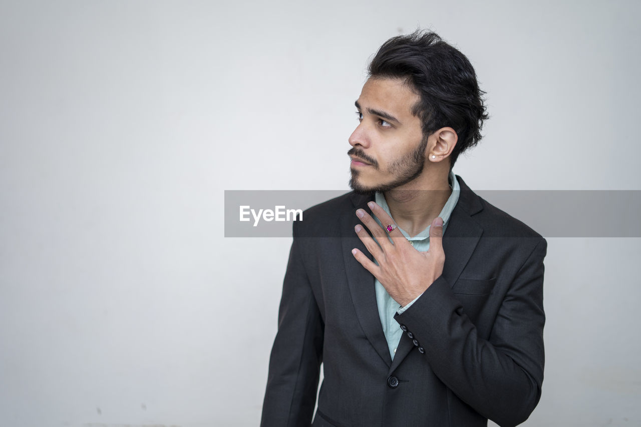 MAN LOOKING AWAY AGAINST GRAY BACKGROUND