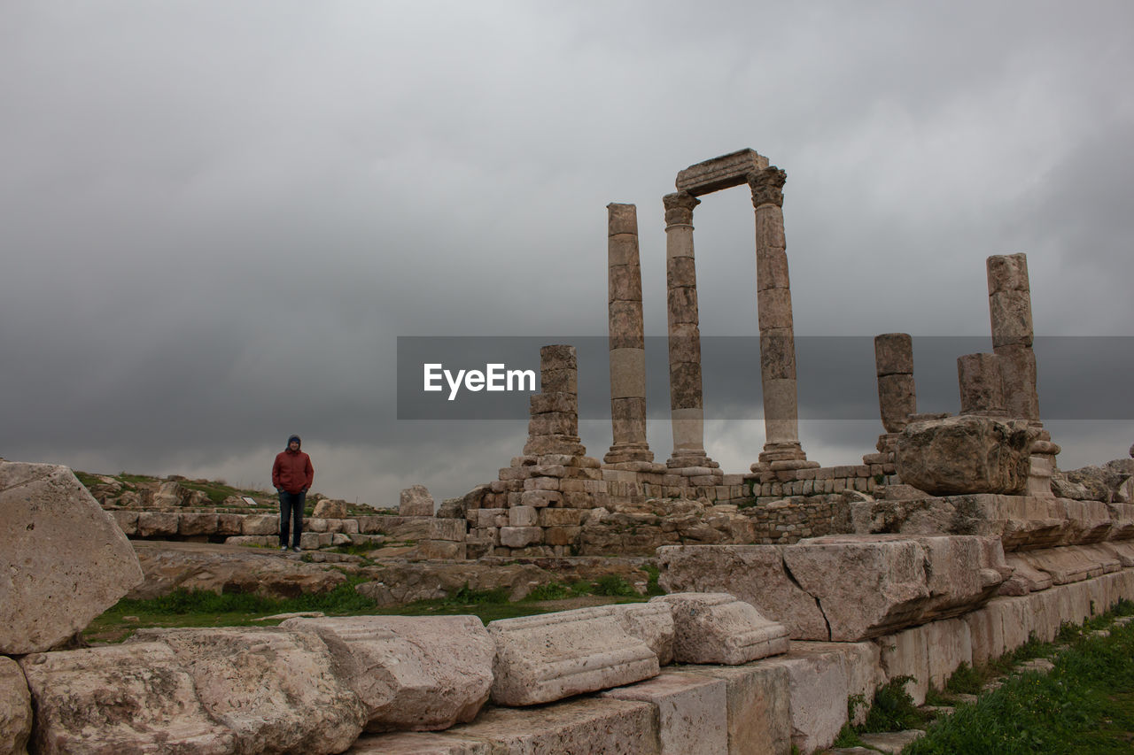 Man standing by temple of hercules against cloudy sky