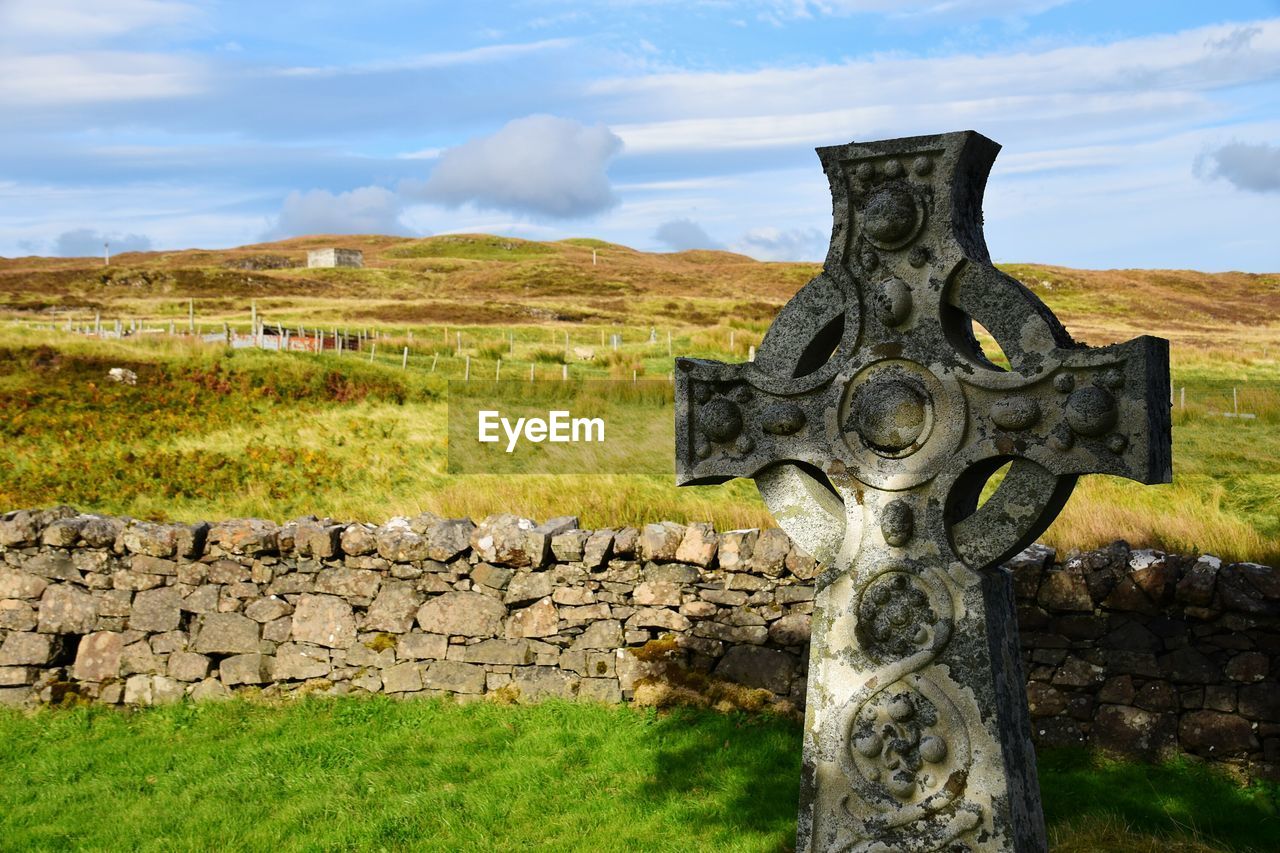 Cross on graveyard against sky