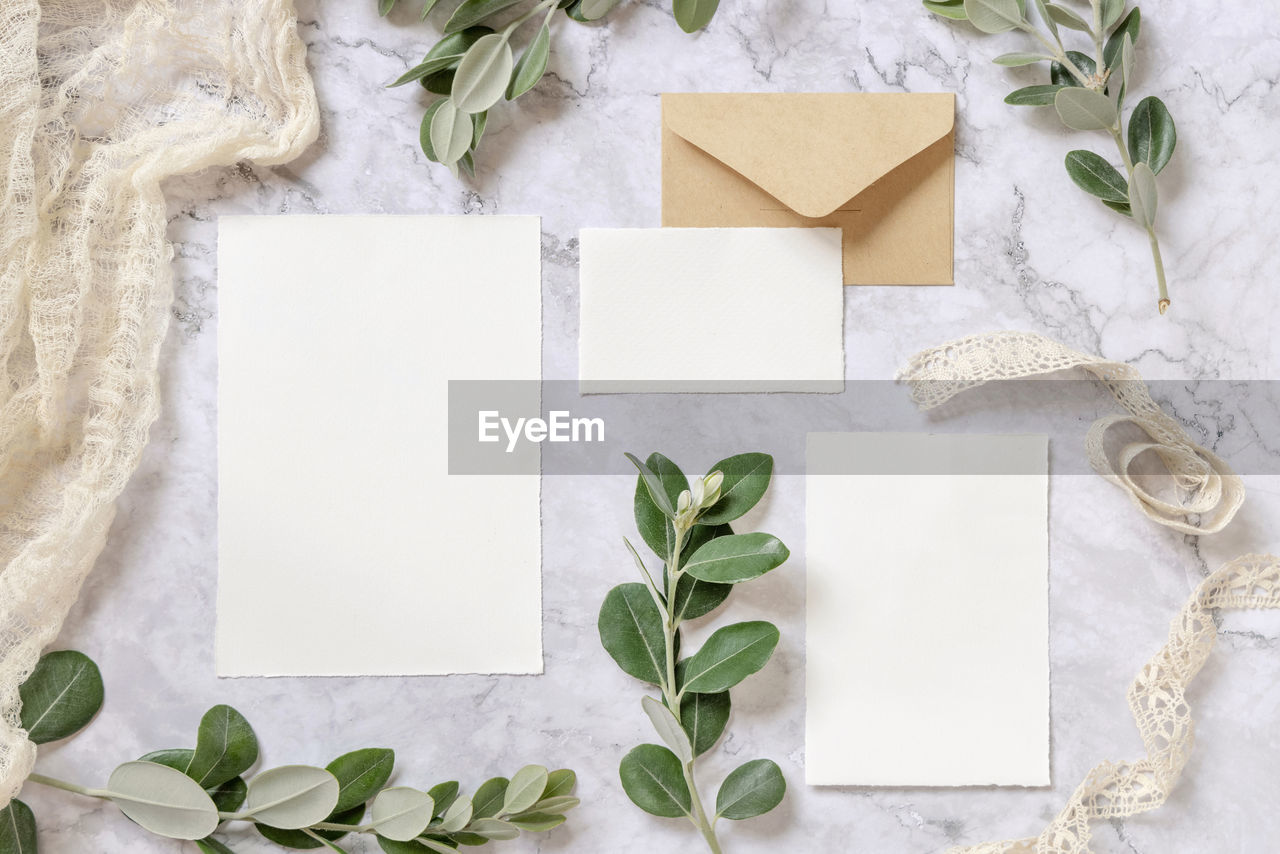 Wedding stationery set with envelope laying on a marble table decorated with eucalyptus and ribbons