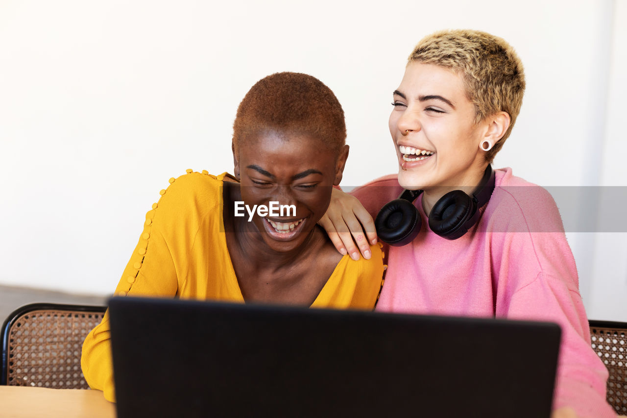 Cheerful lesbian couple looking at laptop