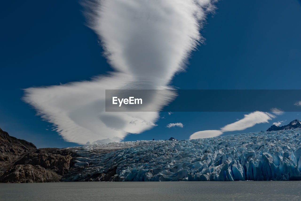 Scenic view of snowcapped mountains by sea against sky