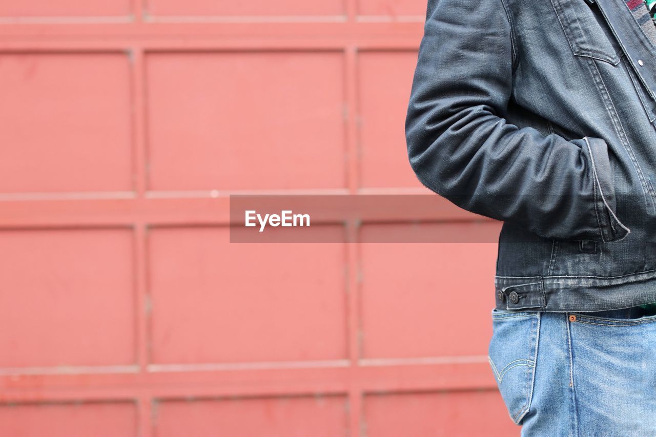 Midsection of man standing against red wall