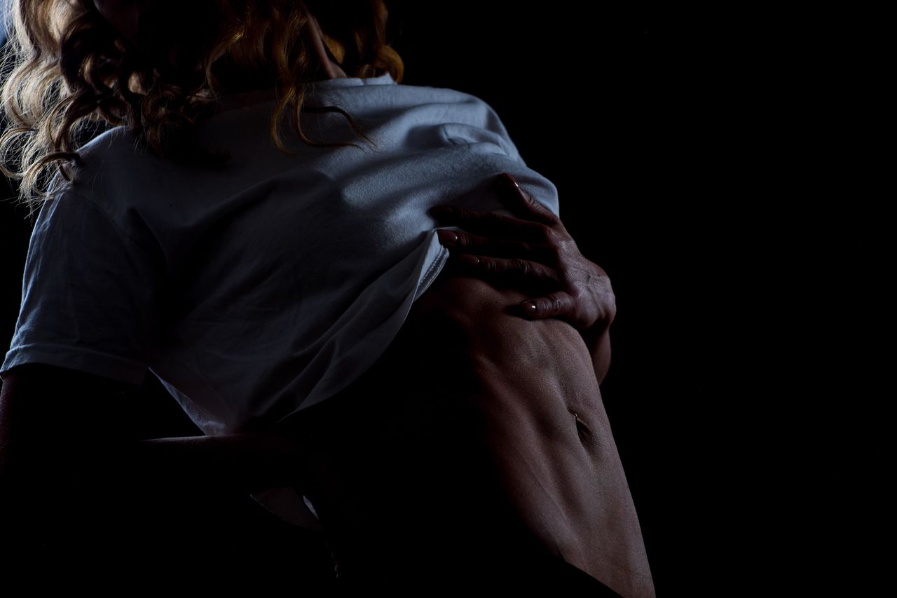 Midsection of female model showing abdominal muscle against black background