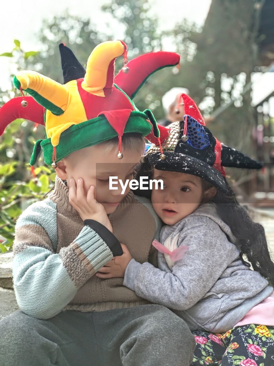 Cute siblings wearing hats sitting outdoors