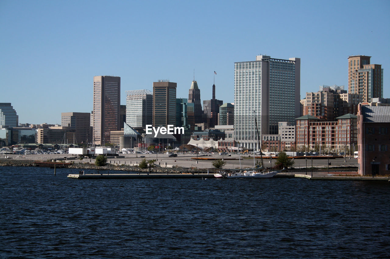 Sea by modern buildings against clear sky