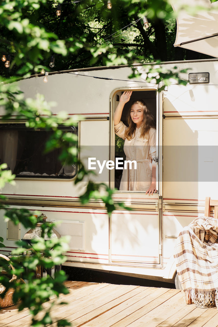 Camping and travelling . happy person relaxing outdoors near trailer. woman is ready for road trip