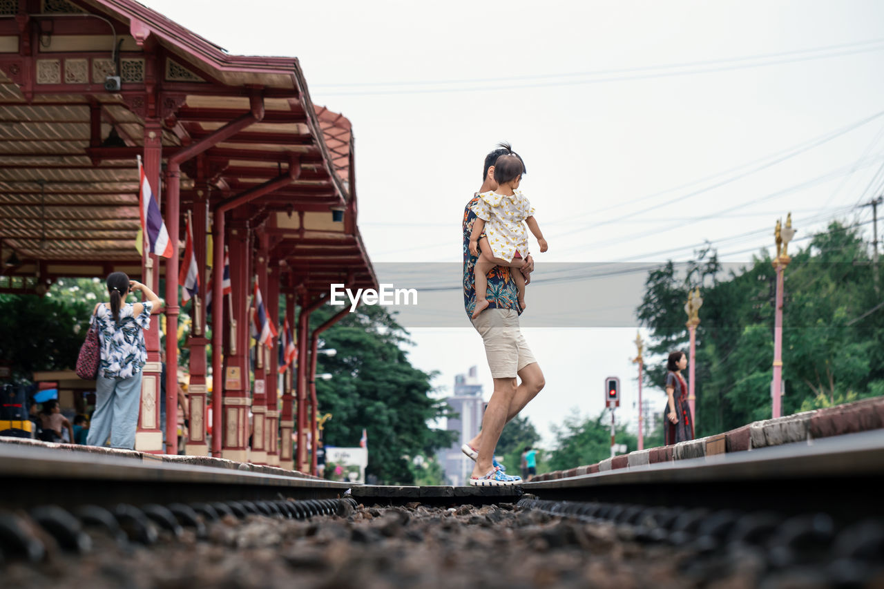 REAR VIEW OF WOMAN WITH UMBRELLA ON RAILWAY BRIDGE